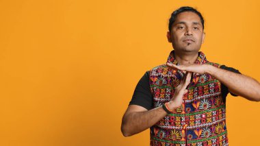 Ciddi bir adam mola istiyor, el hareketleri yapıyor, konsepte devam edemiyor. Cesur insan ısrarla işaret işareti yapıyor. Ara vermek istiyor. Stüdyo arkaplanından izole edilmiş.