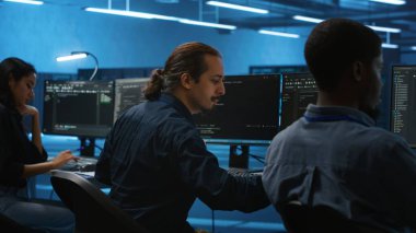 Veri merkezindeki çok ırklı iş arkadaşları bilgisayardaki parametreleri kodlayıp kontrol ediyorlar. Çok ırklı bir ekip birlikte çalışıyor, yüksek teknoloji çalışma alanında programlama yapıyor, sunucu kümelerini denetliyor.