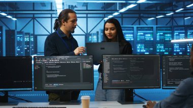Sunucu odasında programcı ve yönetici ekipman düzensizliklerini araştırıyor, beyin fırtınası yapıyor. Veri merkezi vites darboğazlarını kontrol eden çok ırklı meslektaşlar arızalara yol açıyor
