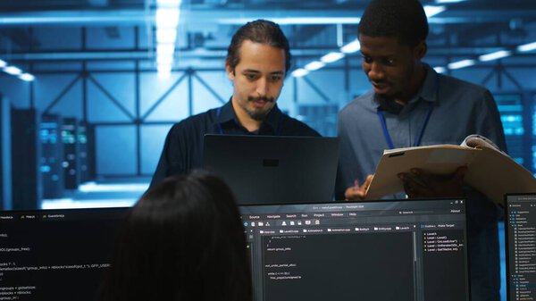 Man inspecting server hub infrastructure, reading paperwork from folder, talking with workers. Supervisor doing evaluation of data center facility workspace, verifying documents