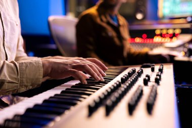 Müzik kayıt stüdyosunda elektronik klavye piyanosuyla notalar çalan erkek şarkıcı, Midi controller synthesizer ile yeni bir hit yaptı. Yetenekli sanatçı kontrol odasında canlı performans sergiliyor..