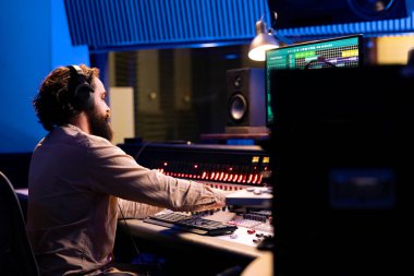 Müzik yapımcısı şarkıları yeni melodiler üretmek için özelleştirir ve düzenler, kayıtlardaki ritme ses efektleri ekler. Ses mühendisliğindeki profesyonel teknisyen kontrol odasında çalışıyor..