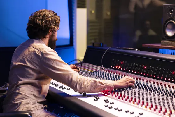 stock image Tracking engineer applying mix and master techniques in studio, pressing buttons and sliders to add sound effects in post production. Skilled producer creating new music with audio console.