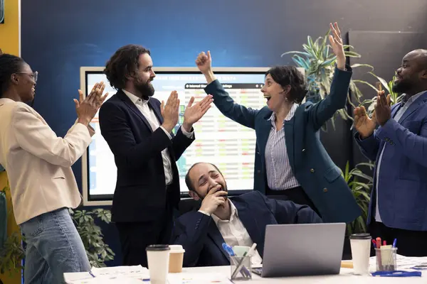 stock image Joyful pleased colleagues celebrating project achievement after looking at sales trends reports, jumping around in the boardroom and feeling proud of their team. Skilled people enjoying success.