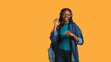 Neşeli Afrikalı Amerikalı kadın mutlu dans ediyor, müzik dinliyor, stüdyo arka planında izole edilmiş. Neşeli insan boş zamanı kutluyor, müzikten hoşlanıyor, pozitif tavır sergiliyor, kamera B
