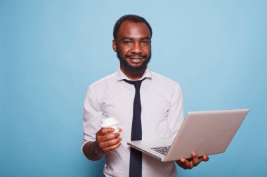Afro-Amerikalı yazar dijital dizüstü bilgisayar ve kahve taşırken kameraya bakıyor. Erkek girişimci içki içerken kablosuz bilgisayar kullanıyor..