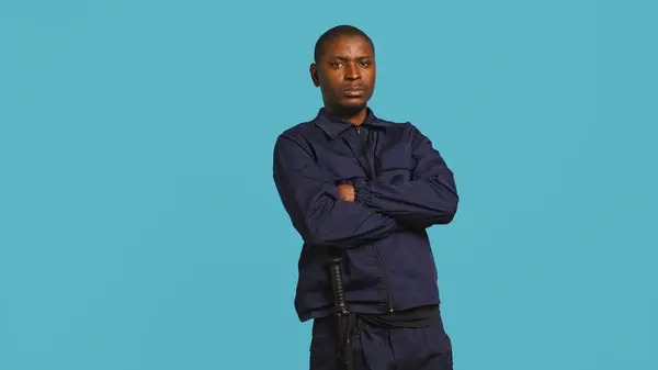 stock image Security guard in threatening pose, tasked with preventing criminal activity and detaining suspects performing crimes. Portrait of menacing bodyguard crossing arms, studio background, camera B