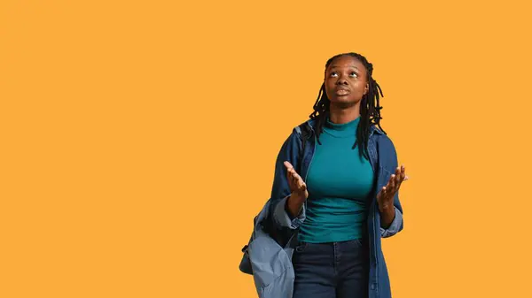 stock image Pious african american woman closing eyes, looking up to sky, waiting for sign from god. Spiritual girl doing worship hand gesturing, spreading arms, hoping for miracle, studio background, camera B