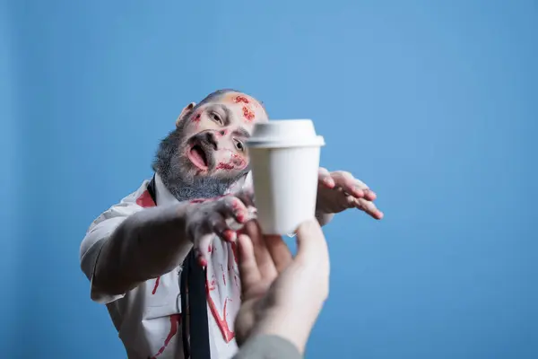 stock image Man starving for coffee, forced by capitalism to maintain productivity all day, being worked to death. Tired employee looking like zombie, needing caffeine to wake up early and work, studio background