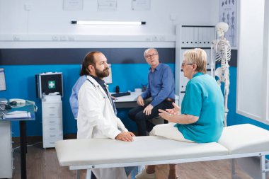 Yaşlı kadın sırt ağrısı için kayropraktöre danışmanlık yapıyor. Kıdemli hasta fiziksel iyileşme için tıbbi yardım ve terapi görüyor. Hastane fizik tedavi uygulamaları ve rehabilitasyon sunuyor..