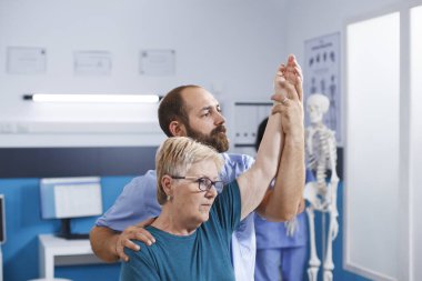 Yaşlı hasta, fizyoterapi ve sırt ağrısı için sağlık uzmanına danışıyor. Emeklilik, osteopati ve profesyonel destekle kinezi terapisi gerektirir..