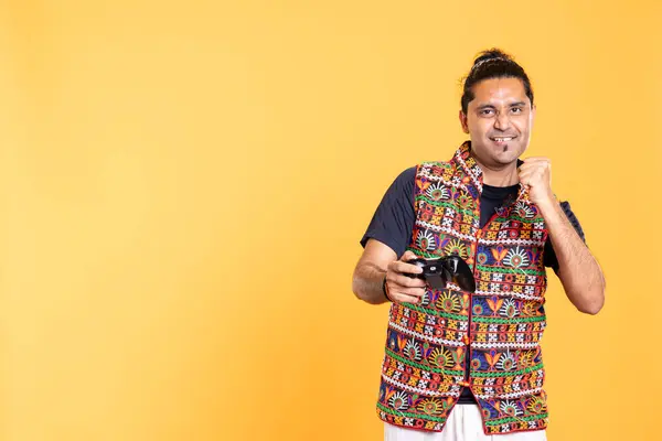 stock image Happy gamer celebrating after winning game on gaming console, studio background. Delighted man bragging after being victorious in videogame, defeating all enemies using gamepad