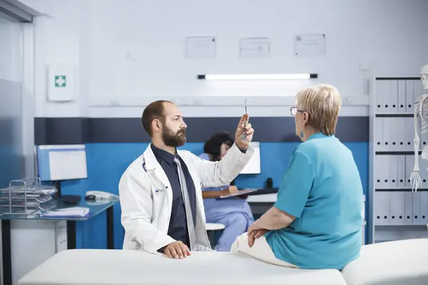 stock image Mature patient sees specialist to recover from back discomfort. Physiotherapist offers advice on workouts and medical assistance. Digital X-ray imaging in a hospital consulting room.