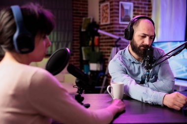 Politika vlog kanalında canlı yayın yapmak için profesyonel video bloglama araçları kullanarak podcast yayınlayan yardımcı sunucular. Kadın ve erkek, neon ışıklarıyla dekore edilmiş oturma odasında film gösterimi için buluşuyorlar.