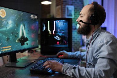 Profesyonel oyuncular online çok oyunculu maça son teknoloji oyun düzeneği ile katılıyor, canlı yayında izleyicileri büyülüyor. Evdeki adam uzay uçan yarış video oyunu oynuyor