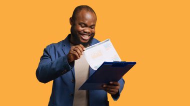 Panodaki mali denetim raporlarına göz atan bir adam yüksek gelirli, stüdyo geçmişinden memnun. Mutlu Afro-Amerikan işçileri not defterine kağıt okuyor, rakamlardan memnun, kamera A