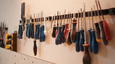 Makaslar, tornavidalar, ingiliz anahtarı ve kerpeten mobilya mağazasında duvarda, çekimler. Marangozlukta ahşap malzemelerle çalışmak için kullanılan çeşitli marangozluk araçlarını kapat