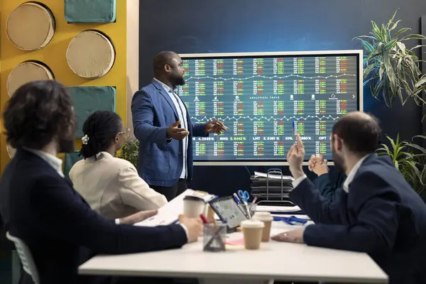 Stock image Business colleagues conducting an informational meeting to share details on projects and arrangements, evaluating the latest economic projections on interactive board to guarantee success.