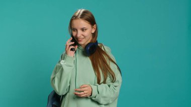 Mutlu kız telefon alıyor, arkadaşlarını selamlıyor, cep telefonu kullanıyor. Ergen, telefon görüşmeleri sırasında okul arkadaşlarıyla sohbet ediyor. Stüdyo arkaplanından izole edilmiş. Kamera A.