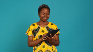 Stüdyoda internet sitelerini kontrol eden mutlu gülümseyen kişi, kabile unsurları olan Afrika etnik kıyafetleri giyiyor. Mutlu bir kız çevrimiçi sosyal medya sitelerine göz atıyor. Kamera A.