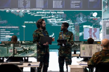 Askeri personel, askerlere görev statüsü ve hedefleri hakkında bilgi vermek için brifing veriyor. Askeri bir güç üssünden keşif için federal uydu sistemi kullanıyor..