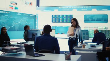 İdari danışman, iş hedeflerine ulaşmak ve küresel ölçekte genişlemek için iş akışını iyileştirmenin yollarını arayarak, performans ölçümleri hakkında görüşmek üzere personelini bir araya getiriyor. Kamera B.