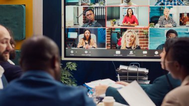 İş ortakları, yeni bir kalkınma projesi hakkında bilgi ve güncellemeleri paylaşmak üzere bir video çağrısı bağlantısı hakkında hissedarlarla görüşüyor. Yönetim kurulu üyeleri sıkı büyümeyi tartışıyor. Kamera A.