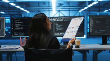 Belden aşağısı felçli biri sunucu merkezinde çalışıyor elektronik aletleri inceliyor, dosyaları okuyor. Tekerlekli sandalye kullanıcısı evrakları inceliyor, altyapı belgelerini doğruluyor, denetim yapıyor