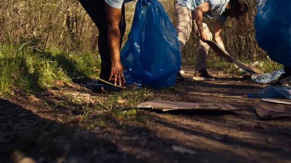 İnsanlar orman bölgesinden çöp ve plastik şişe topluyor, doğal çevreyi koruyor ve gönüllü iş yapıyorlar. Eylemciler ormanı temizliyor, atıkları geri dönüştürüyor. Kamera B.