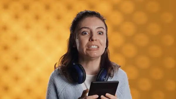 stock image Voice actor reading ebook in entertaining manner in front of audience, portraying character, studio background. Woman reenacting digital novel for spectators, reading from tablet screen, camera A