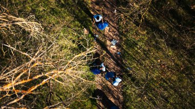 Aerial view of campaigners joining forces to recycle and tidy up garbage in a forest in order to safeguard the ecosystem. Individuals having ecologic conservation principles, eco friendly. clipart