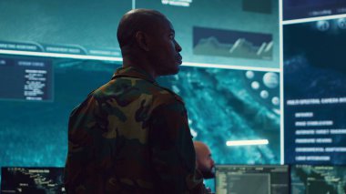 Ordu komutanı, kontrol merkezindeki özel keşif görevine nezaret ediyor. Gizli kamera görüntüleri ve büyük ekranda bir dünya haritası olan istihbarat toplama operasyonlarını yürütüyor. Kamera A.