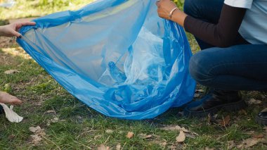 Geri dönüşüm için çöp ve plastik atık toplayan aktivistlerden oluşan bir ekip çöp temizleme araçları ve çöp torbalarıyla ormanı temizliyor. Ormandan çöp toplayan insanlar, aktivizm. Kapatın. Kamera A.