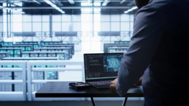 Sunucu merkezindeki mühendis insan beyni simülasyonu yapan yapay zeka bilgisayarlı modelle çalışıyor. Yapay zeka makinesi ile dizüstü bilgisayarda çalışan adam örüntü tanıma algoritması, kamera B ile çalışıyor.