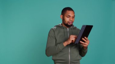 Neşeli adam tablet kullanarak internet sitesine ödeme metodu ekliyor. Cihaz kullanarak internet alışverişi yapmaktan heyecan duyan kişi, bankamatik kartı verileri, stüdyo arkaplanı üzerinden izole edilmiş, kamera B