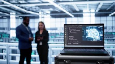 Bulanık arka planda mühendisler tarafından kullanılan yapay zekaya sahip veri merkezindeki dizüstü bilgisayara odaklan. Sunucu çiftliğinde yapay zeka öğrenme yazılımını gösteren aygıtı kapat, kamera B