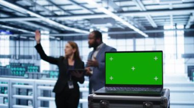 Sunucu odasını izleyen mühendisler tarafından kullanılan yeşil ekran dizüstü bilgisayarı. Bilgi işlem merkezinde çalışan IT çalışanı tarafından kullanılan krom anahtar deftere odaklan, B kamerası kapat