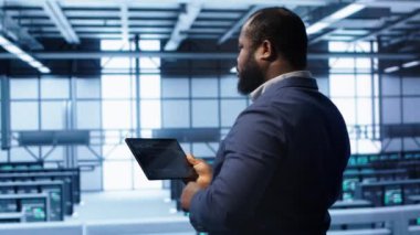 Sunucu odasındaki bilişim operatörü aktarım hızlarını etkileyen ağ sorunlarını düzeltmek için tablet kullanıyor. Veri merkezinde sunucu sıralarını etkileyen hataları düzelten mühendis, kamera A