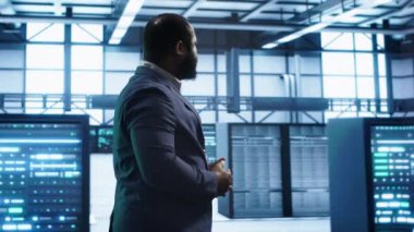 Veri merkezinde yürüyen Afrikalı Amerikalı teknisyen, hataları tespit etmek için sistemleri izliyor. Sunucu merkezindeki adam teşhis koyuyor, onarılması gereken altyapı hataları arıyor, kamera A