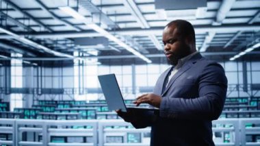 Veri merkezinde dizüstü bilgisayarda yazan programcı, hata kontrol araçları çalıştırıyor. Bilgi İşlem uzmanı sunucu odasında, dijital aygıt, kamera B kullanarak sondaj performansını etkileyen ağ sorunları arıyor