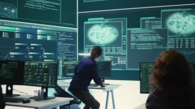 Hükümet hackerları siber tehditlere karşı korunmak için gelişmiş yazılım kullanıyor, ekip halinde çalışıyorlar. Siber güvenlik, veri ve ağ koruma uzmanları yüksek teknoloji ofisinde güçlerini birleştiriyor. Kamera B.