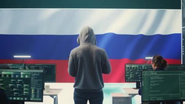 Hükümetin hackleme odasında Rus bayrağı büyük ekranda çalışan bir Rus bilgisayar korsanı. Siber terör, propaganda, sahte haberler ve hibrid savaşta yanlış bilgilendirme. Kamera B.