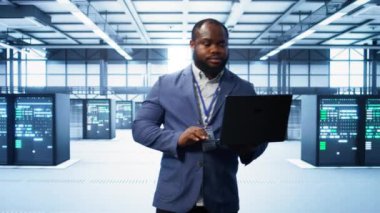 Modern veri merkezinde dizüstü bilgisayar üzerinde çalışan bilişim mühendisi, sunucu işlemleri, sistem bakımı ve siber güvenlik protokolleri, optimal performans ve veri bütünlüğü sağlanması, kamera B