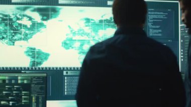 Siber güvenlik ekibi bir hükümet kontrol odasında siber gözetleme yapıyor. Uzman grup hackleme faaliyetleri, kötü amaçlı yazılım koruması ve yüksek teknoloji ajansında veri sızıntısını önleme. Kamera A.
