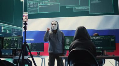 Maskeli anonim kişi ulusal bayrağıyla Rus hükümetinin hackleme odasında fidye istiyor. Siber casusluk, yanlış bilgilendirme kampanyaları ve melez savaş propagandalarıyla uğraşmak. Kamera B.