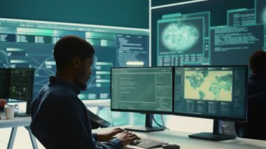 Hükümet hackerları siber tehdit tespiti için verileri analiz ediyor, yüksek teknoloji ofisindeki büyük ekrana bakıyor. Siber istihbaratı, çevrimiçi güvenliği ve dijital tehditleri önlemeyi vurgula. Kamera B.