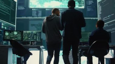 Hükümet hackerları büyük ekranlardaki siber tehditleri analiz ediyor, yüksek teknoloji ofisindeki önemli veritabanı hackleme faaliyetlerini yönetiyor. Ulusal güvenliği korumak için siber savunma üzerinde çalış. Kamera B.