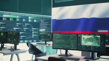 Büyük ekranda Rus bayrağı dalgalanan, siber terörizm ve propaganda tehdidini gösteren boş otokrasi siber savunma odası. Rus hackerların sahte haberler yayma faaliyetleri. Kamera B.
