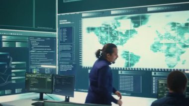 Siber savunma ekibi bir hükümet güvenlik operasyon merkezinde çalışıyor. Uzmanlar siber suçları önleme ve veri sızıntısı korumasını güvence altına alarak büyük ekranda bilgi inceliyorlar. Kamera B.