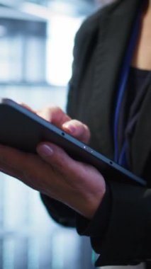 Dijital cihaz kullanarak ileri teknoloji ile veri merkezini yöneten dikey video bilimcisi. Sunucu odasında tablet, kamera B ile veri merkezi donanımını optimize eden kişinin yakın plan görüntüsü